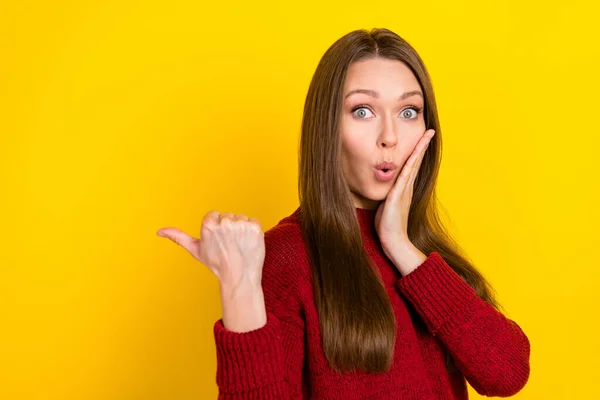 Фотографія з боку профілю молодої жінки, вражена шокованою фальшивою новинкою, вказує на великий палець порожній простір реклами ізольовано на жовтому кольоровому фоні — стокове фото