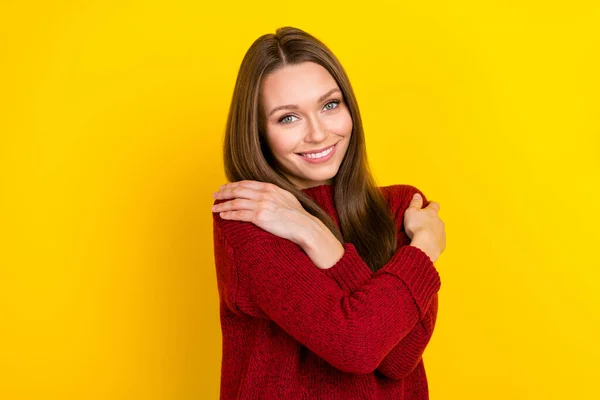 Портрет привлекательной веселой длинноволосой девушки, обнимающей себя теплой одеждой, изолированной на ярко-желтом фоне — стоковое фото