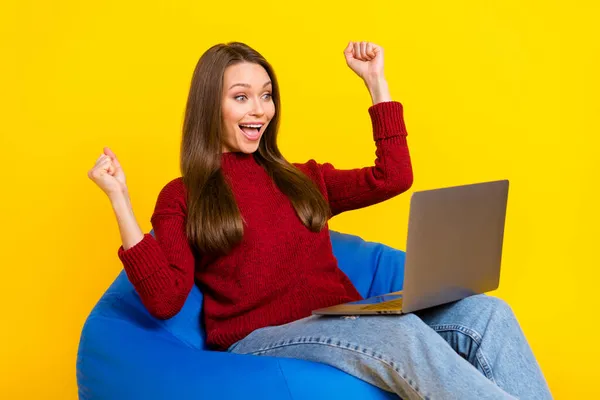 Zdjęcie szczęśliwy miły młoda kobieta zdumiony wygrać uchwyt laptop siedzieć krzesło izolowane na żółtym tle kolor — Zdjęcie stockowe