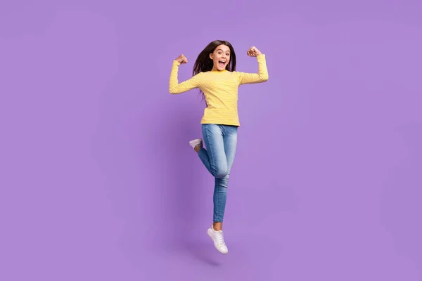 Foto de cuerpo entero de una joven deportista mostrar brazos músculos ejercicio salto aislado sobre fondo de color violeta —  Fotos de Stock