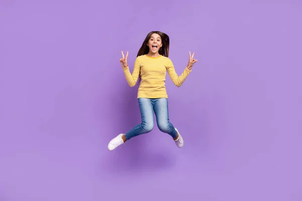 Foto de tamaño completo de la joven dama alegre salto mostrar los dedos v-símbolo hola viaje aislado sobre fondo de color púrpura — Foto de Stock