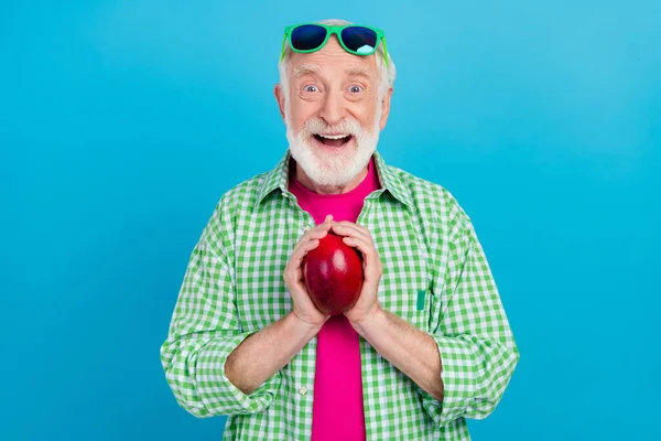 Foto di felice eccitato positivo vecchio nonno tenere mango vacanza frutta mangiare godere isolato su sfondo di colore blu — Foto Stock