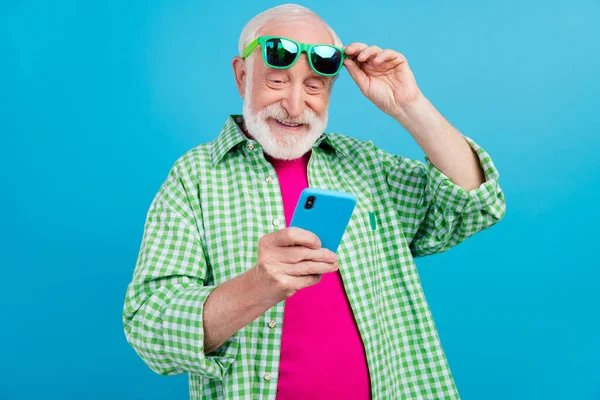 Mutlu, pozitif, yaşlı emeklinin fotoğrafı. Yaşlı büyükbaba el ele tutuşup mavi arkaplanda izole edilmiş mesajları kontrol ediyor. — Stok fotoğraf