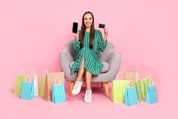 Полноразмерная фотография молодой женщины, покупающей кредитную карту в мобильном магазине, выделенная на цветном фоне — стоковое фото