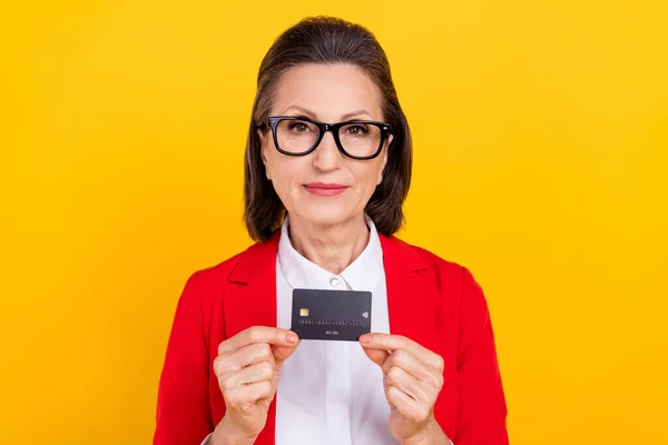Foto do gerente mais velho morena senhora mãos cartão desgaste óculos vermelho casaco isolado no fundo de cor amarela — Fotografia de Stock