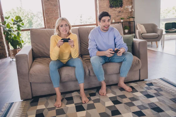 Retrato de atractiva pareja alegre sentado en diván jugando juego pasar fin de semana en casa loft interior industrial en interiores — Foto de Stock