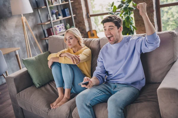 Retrato de pareja alegre atractiva sentada en diván viendo programa de televisión divirtiéndose en casa loft interior industrial interior — Foto de Stock