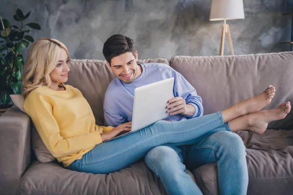 Foto de joven alegre pareja feliz sonrisa positiva ver leer navegar portátil en línea sentarse sofá en el interior — Foto de Stock