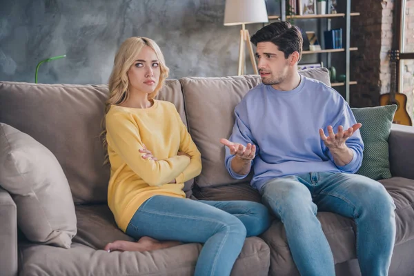 Foto de pareja joven infeliz negativo conflicto de mal humor argumento ofendido hablar sentarse sofá interior — Foto de Stock