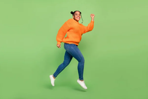 Foto de perfil de comprimento total de engraçado millennial morena senhora executar desgaste camisola jeans calçado isolado no fundo verde — Fotografia de Stock