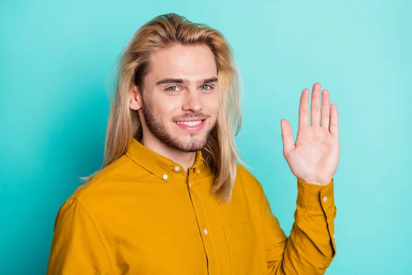 Photo of young handsome man happy positive smile waving hand hello hi isolated over teal color background — Stockfoto