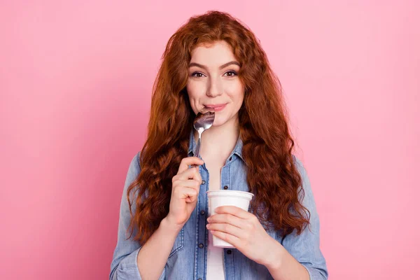 甘い空腹の若い女性の写真はデニムシャツを着て準備ができて食べるヨーグルト舐めスプーン笑顔孤立ピンク色の背景 — ストック写真