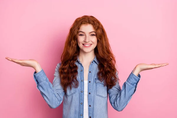 Foto van zoete charmante jonge vrouw dragen denim shirt tonen schubben houden armen lege ruimte glimlachen geïsoleerde roze kleur achtergrond — Stockfoto