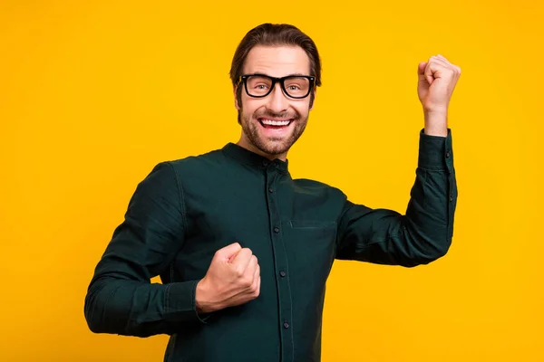 Foto do jovem sortudo positivo vestido inteligente roupas casuais óculos sorrindo levantando punhos isolado cor amarela fundo — Fotografia de Stock
