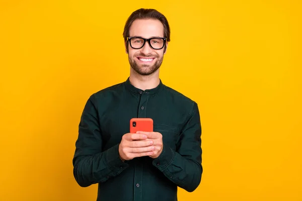 Foto de alegre jovem positivo vestido inteligente casual roupas óculos comunicando gadget moderno isolado cor amarela fundo — Fotografia de Stock