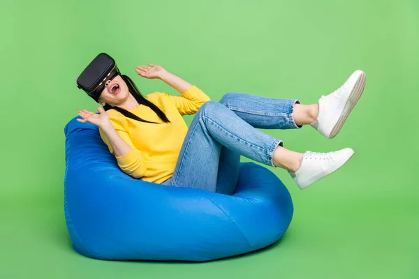 Portret dość wesoły dziewczyna siedzi na torbie krzesło noszenie kask VR zabawy grając w grę izolowane na jasnozielonym tle kolor — Zdjęcie stockowe