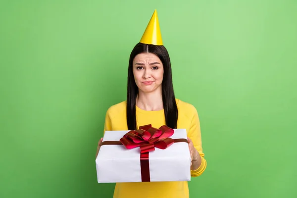 Çekici şüpheci kızın portresi, yeşil arka planda hoş olmayan izole edilmiş hediye kutusunu tutuyor. — Stok fotoğraf