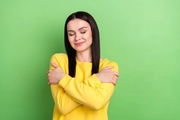 Ritratto di attraente ragazza sognante che si abbraccia indossando vestiti morbidi isolati su sfondo di colore verde — Foto Stock