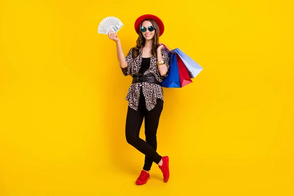 Full length φωτογραφία του μελαχρινή ευτυχισμένη ωραία γυναίκα κρατήστε τα χρήματα τσάντα ψώνια χέρι απομονώνονται σε κίτρινο χρώμα φόντο — Φωτογραφία Αρχείου