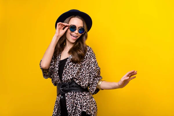 Φωτογραφία του funky γοητευτικό ευτυχισμένη νεαρή γυναίκα καλή διάθεση φορούν μαύρα γυαλιά καπέλο απομονώνονται σε κίτρινο χρώμα φόντο — Φωτογραφία Αρχείου