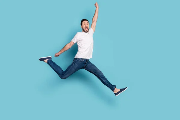 Full storlek profil sida foto av galna glada ung man hoppa upp höja handen vinnaren isolerad på blå färg bakgrund — Stockfoto