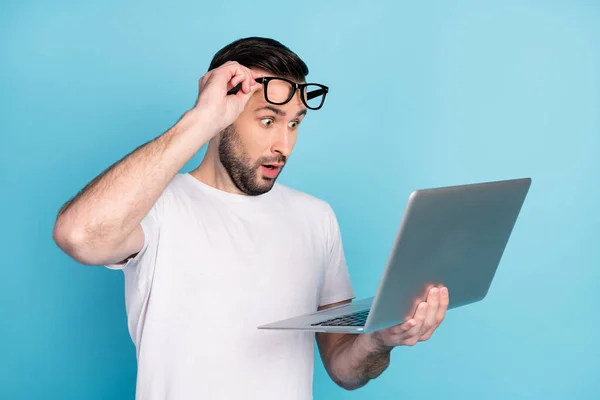 Foto van onder de indruk man arm het nemen van een bril open mond staren laptop geïsoleerd op blauwe kleur achtergrond — Stockfoto