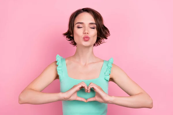 Foto de penteado bob romântico jovem senhora golpe beijo mãos coração desgaste teal top isolado no fundo cor-de-rosa — Fotografia de Stock