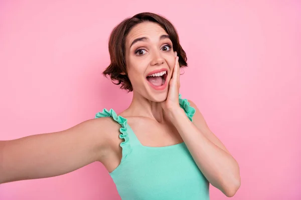 Photo of astonished brown hairdo millennial lady do selfie wear teal top isolated on pink color background — Foto Stock