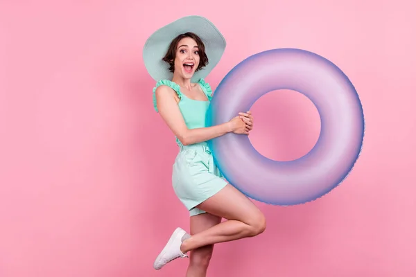 Retrato de menina extática alegre atraente segurando anel de borracha ter praia divertida isolada sobre fundo de cor pastel rosa — Fotografia de Stock