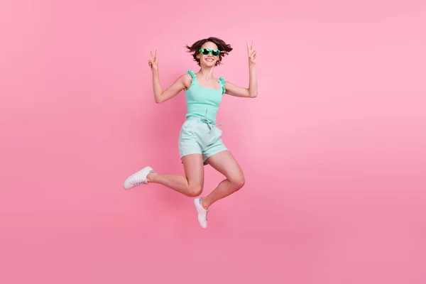 Volledige lengte foto van grappige korte kapsel jonge dame springen dragen teal top shorts brillen geïsoleerd op roze kleur achtergrond — Stockfoto