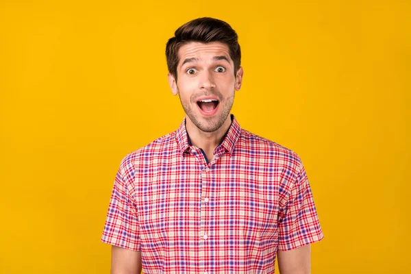Портрет привабливого здивованого веселого брюнетки хлопець у перевіреній сорочці ізольований на яскраво-жовтому кольоровому фоні — стокове фото