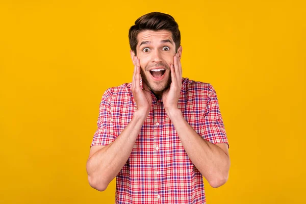 Fénykép csodálkozó megdöbbent fiatal boldog férfi fogja kezét arcát hírek eladó elszigetelt sárga színű háttér — Stock Fotó
