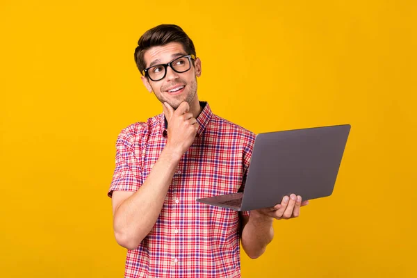 Foto von fröhlichen jungen glücklichen Mann suchen leeren Raum denken halten Laptop Freelancer isoliert auf gelbem Hintergrund — Stockfoto