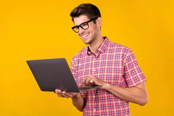 Photo of happy positive young man hold hands look laptop wear glasses businessman isolated on yellow color background.