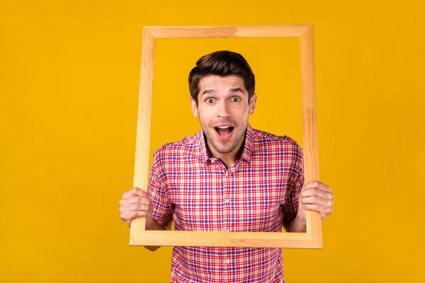 Photo of amazed happy shocked young man hold hands frame image isolated on shine yellow color background — Foto Stock