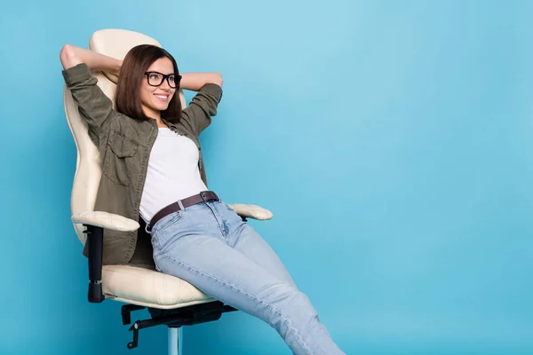 Foto wanita ceria positif duduk tangan kursi beristirahat mengenakan pakaian khaki terisolasi di atas biru latar belakang warna — Stok Foto