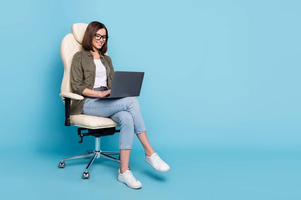 Полное фото тела менеджера дамы сидеть кресло использовать устройство нетбук онлайн общаться носить джинсы изолированы на синем фоне цвета — стоковое фото