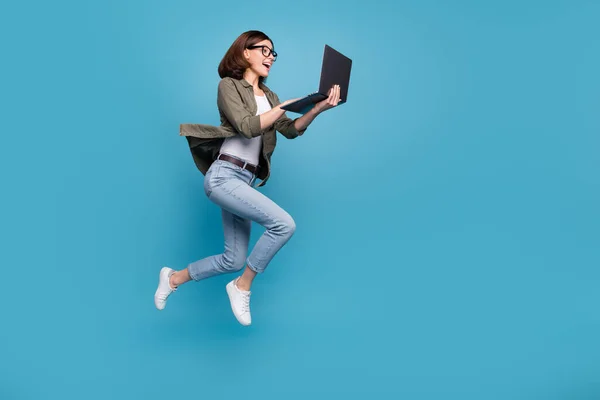 Profilseite Foto in voller Größe von aufgeregten Dame ceo springen Chat Netbook ap tragen Jeans isoliert über blauen Farbhintergrund — Stockfoto