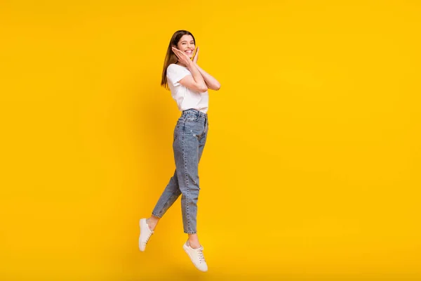フルサイズの写真の幸せな正の若い女性ジャンプアップ手を保持顔笑顔孤立した黄色の色の背景 — ストック写真