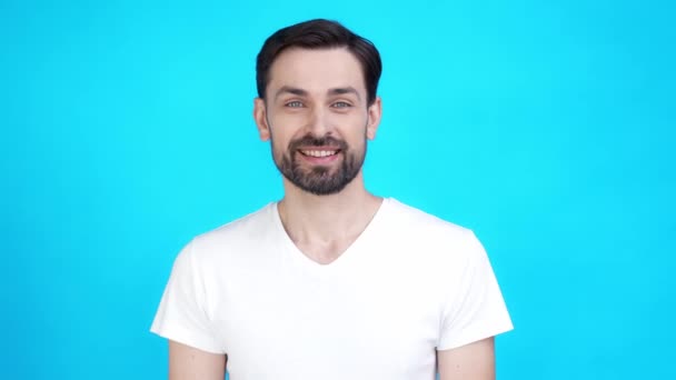 Radostný chlap vypadat zubatý úsměv ve fotoaparátu izolované na modrém pozadí — Stock video