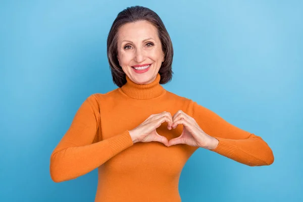 Zdjęcie uroczej pozytywnej osoby w wieku ramiona palce zrobić symbol serca izolowane na niebieskim tle koloru — Zdjęcie stockowe