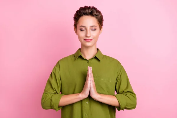Fotografie zasněný hezká mladá žena oblečená zelená košile zavřené oči paže spolu cvičí jógu izolované růžové barvy pozadí — Stock fotografie