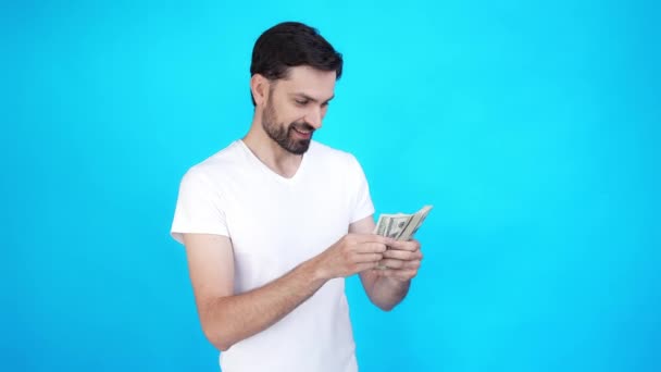 Delighted guy check earnings throw cash fall blue color background isolated — Stock Video