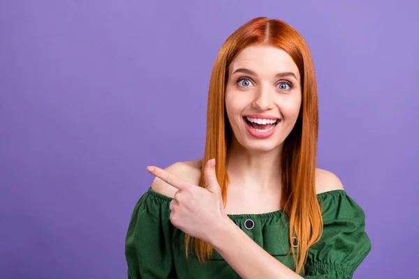 Фото чарівної враженої жінки, одягненої в плечі блузка посміхається вказуючи палець порожній простір ізольований фіолетовий кольоровий фон — стокове фото