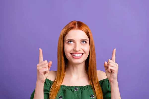 Фотографія враженої милої молодої жінки, одягненої в плечі блузка посміхається, вказуючи на порожній простір ізольований фіолетовий кольоровий фон — стокове фото