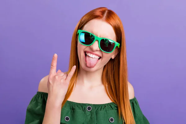 Foto de cabello de jengibre funky joven dama mostrar señal de roca usar gafas blusa verde aislado sobre fondo violeta —  Fotos de Stock