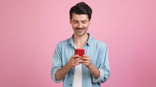 Vrolijke mooie knappe nieuwsgierige man houden telefoon sms 'en blik lege ruimte — Stockvideo