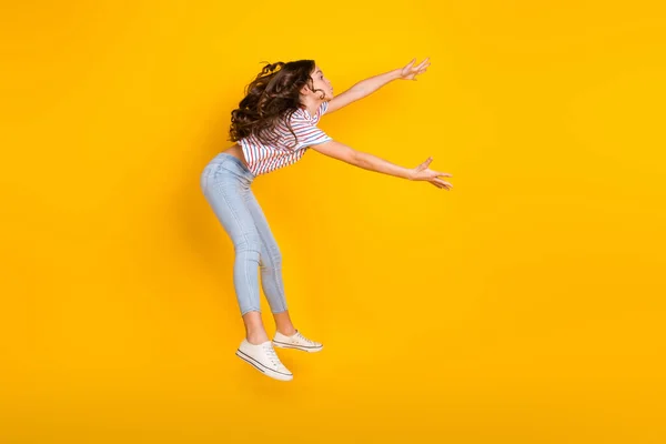 Foto lateral de perfil de longitud completa de la joven niña preadolescente saltar por el viento golpe captura aislado sobre fondo de color amarillo — Foto de Stock