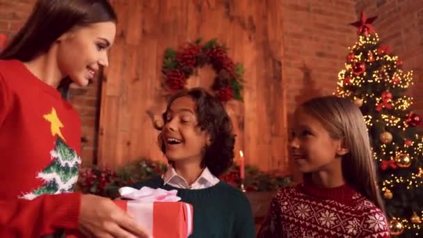 Zoom-out ver emocionados niños pequeños reciben Noel presente reunión familiar en el interior — Vídeo de stock