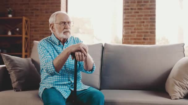 Pensif esprit grand-père assis canapé tenir bâton de marche détourner le regard penser — Video